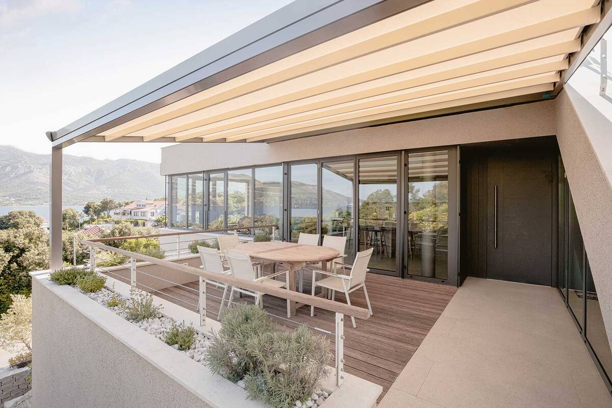 Die Pergola «Sintesi» kombiniert innovatives Design mit präziser Tuchführung und schlanken Führungsschienen. Die edle Überdachung spendet Schatten und bietet gleichzeitig Schutz vor Wind und Regen. Hella Storen AG.
