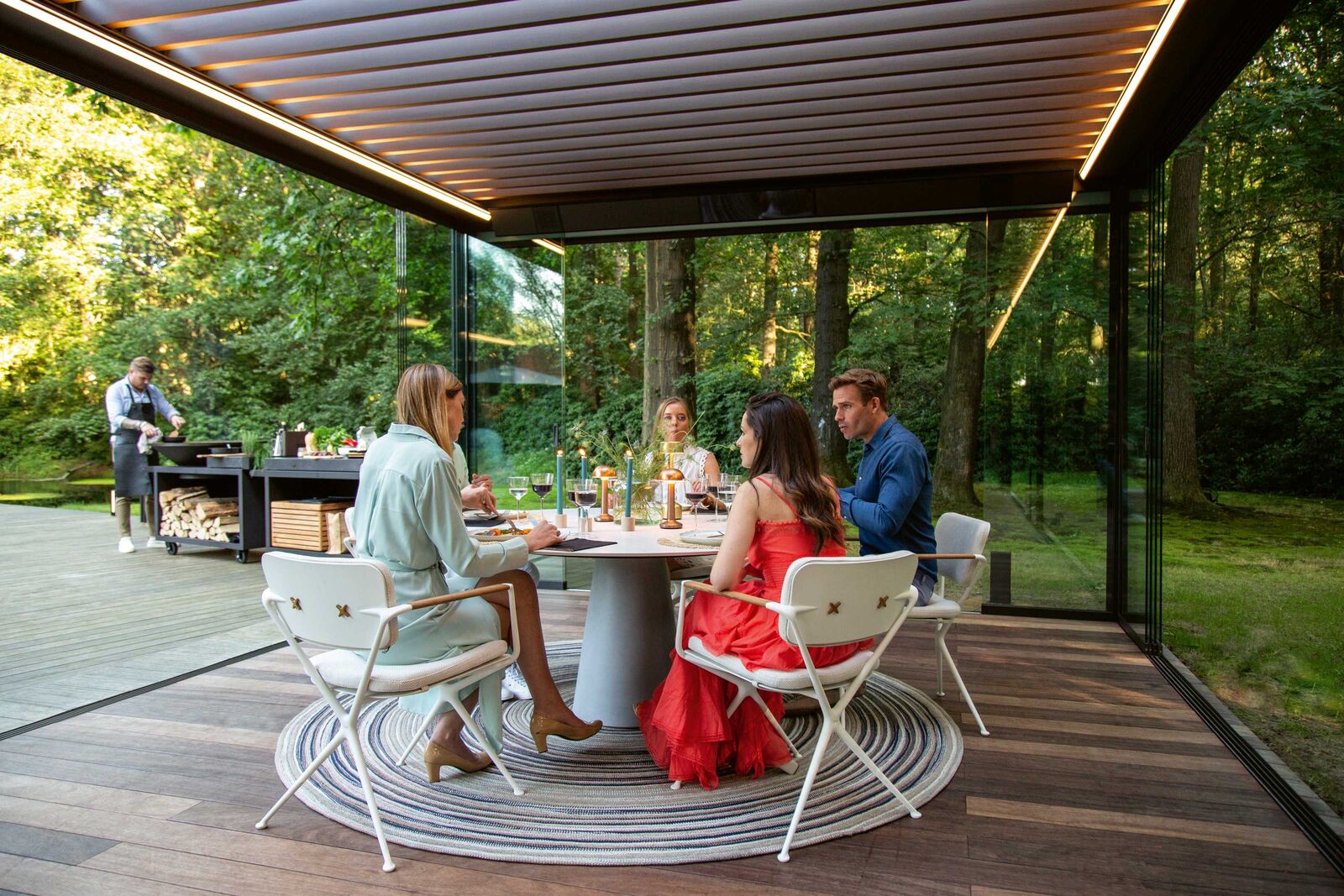 Mit einem festen Lamellendach und Seitenwänden aus Glas wird die Terrasse zum wettergeschützten Raum.