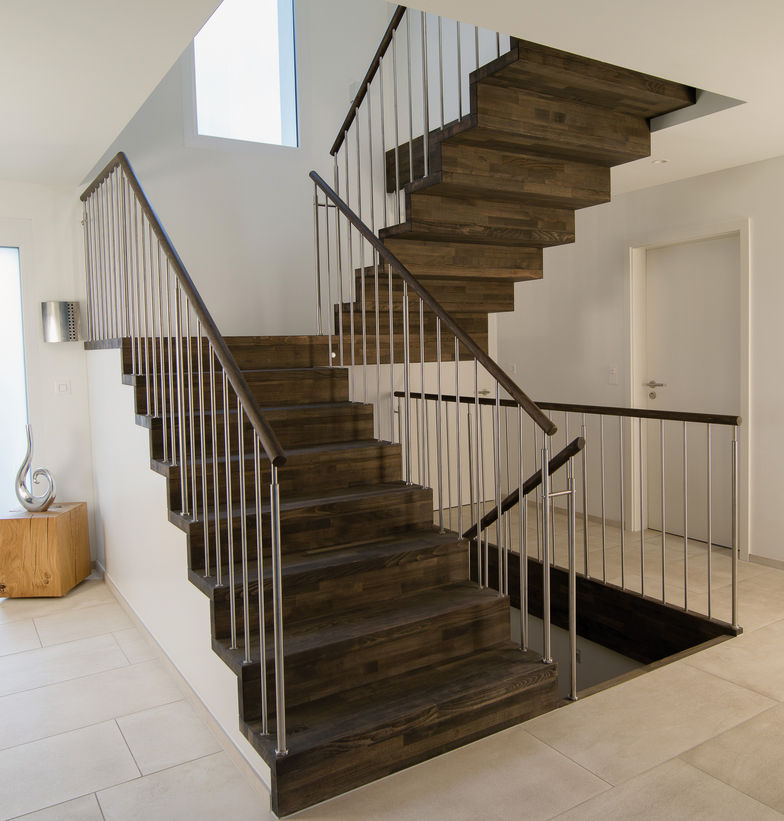 Schwarz geölte Stahlblech-Faltwerktreppe mit Stufen in Buche bunt längsgezinkt. Sprossengeländer in Edelstahl mit Holzhandlauf. Keller Treppenbau.